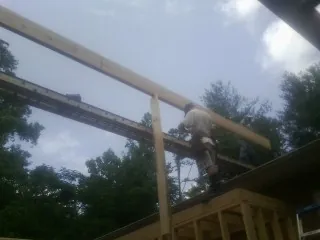 Carpenter setting a ridge beam over a new addition frame — Ice Dam Removal by Roofing Brothers in Bennet