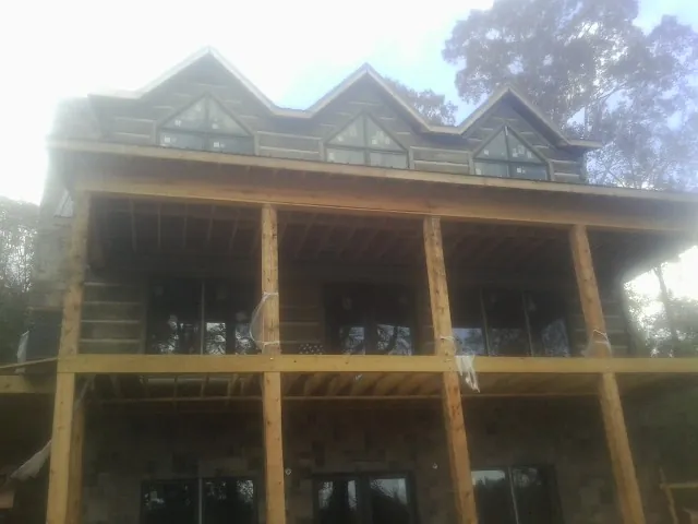 Dormers and porch framing on a large log home under construction — Roof Coating work by our crew in Bennet