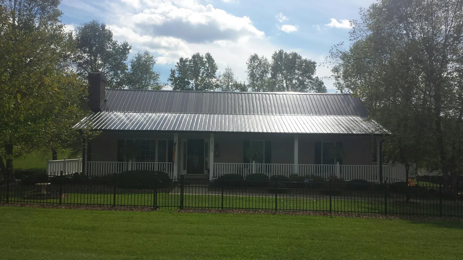 Gray metal roof on a brick ranch with a full width front porch — Gutter Guard Installation work by our crew in Bennet