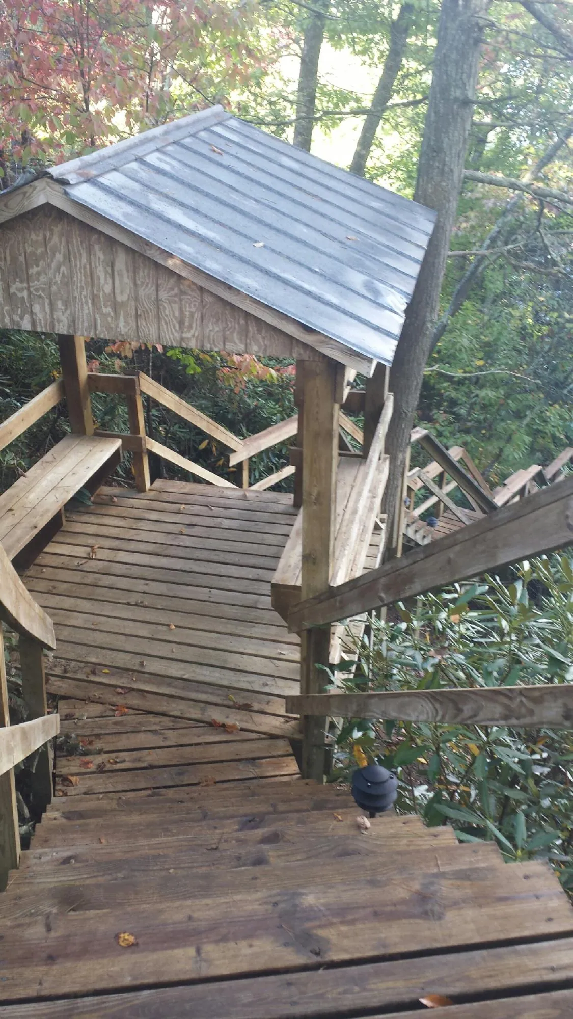 Metal roofed shelter over wooden steps on a wooded walkway — Skylight Repair & Installation work by our crew in Bennet