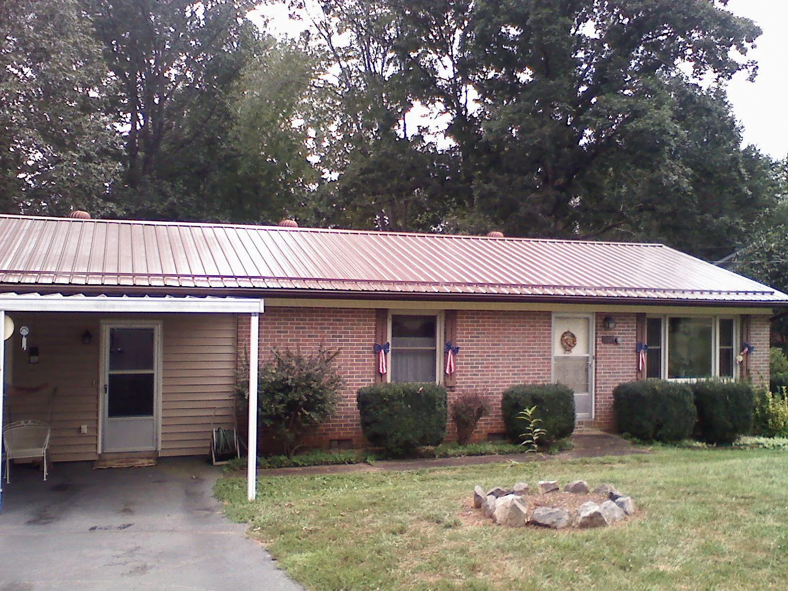 Bronze metal roof and carport on a brick ranch home — Roof Repair work by our crew in Bennet