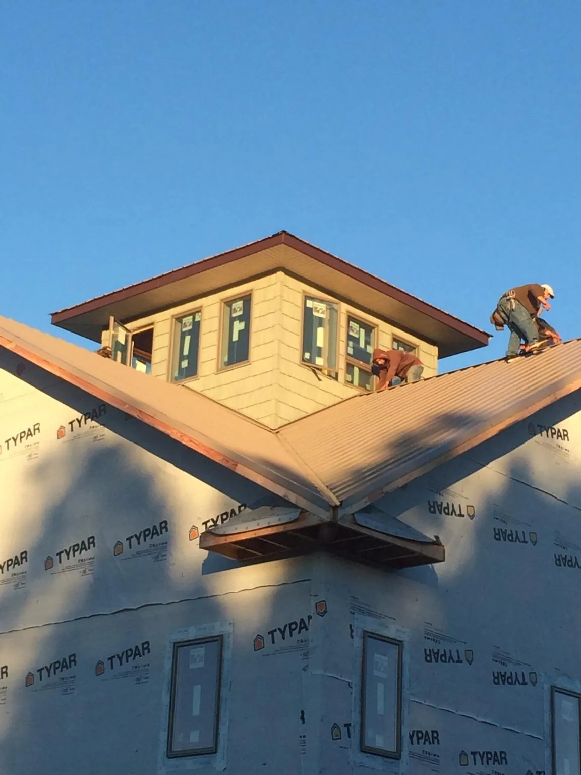 Roofers working around a rooftop cupola on a new metal roof at sunset — Roof Waterproofing in Bennet by Roofing Brothers